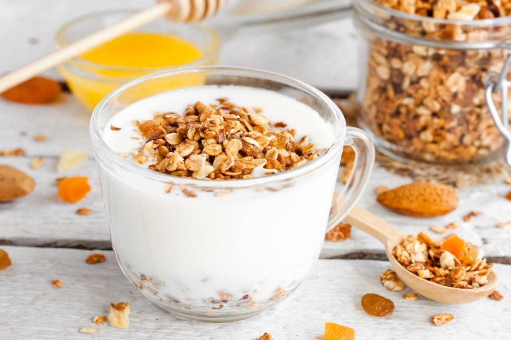 yogurt with homemade granola, nuts and dried fruits in a glass cup