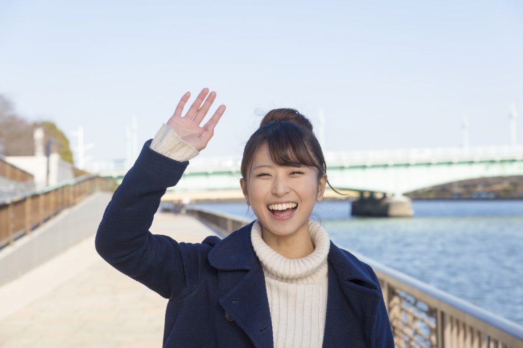 笑顔で手を降る女性のイメージ画像