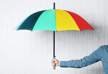 Colorful umbrella in male hand on wall paneling background