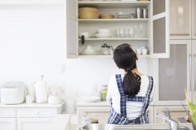 キッチンの棚を見上げる女性