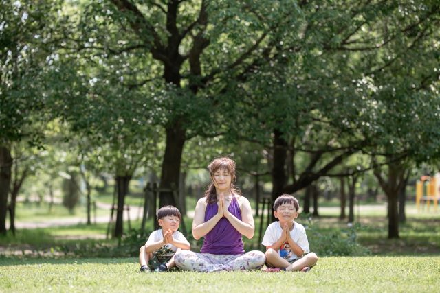 公園で子供とヨガをする女性