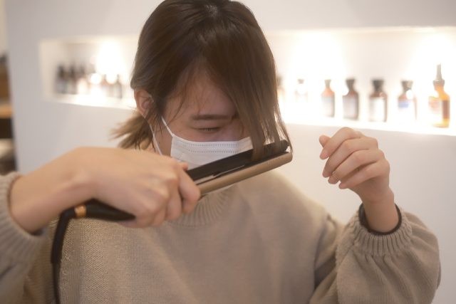 前髪にヘアアイロンをあてる女性