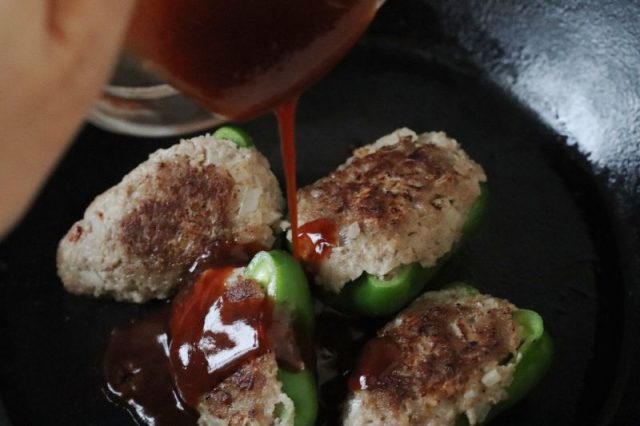 タレをかけているピーマンの肉詰め