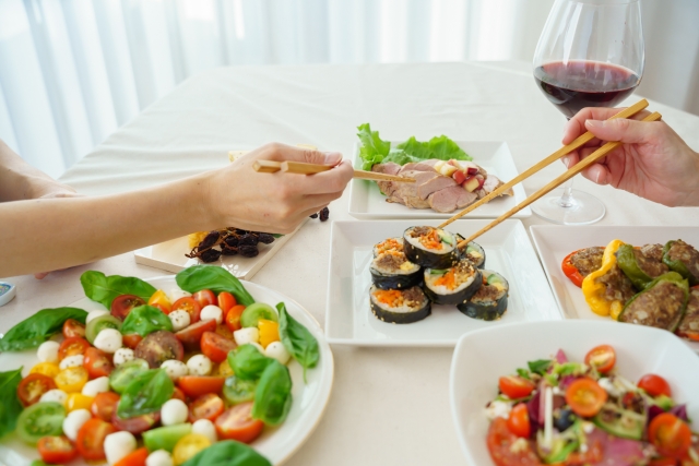 箸を持つ人と大皿料理