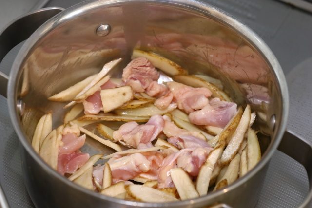 鍋で鶏もも肉とごぼうを炒める
