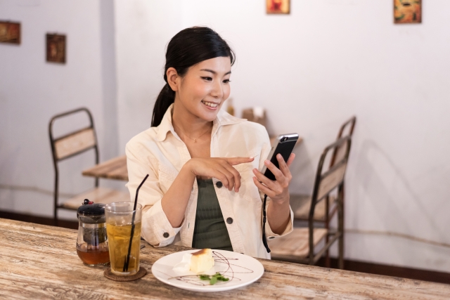 スマホを指さす女性