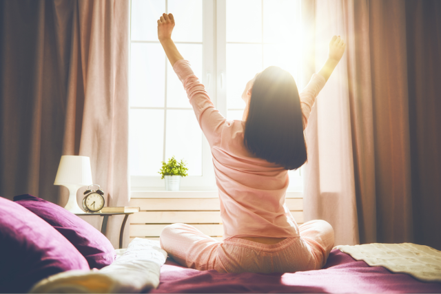 窓辺で伸びをする女性