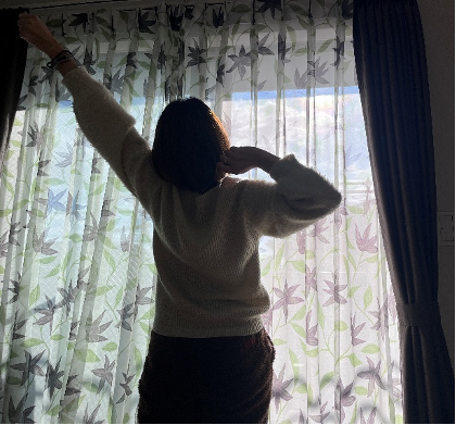 窓際で伸びする女性