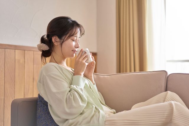 朝、あたたかい飲み物を飲む女性