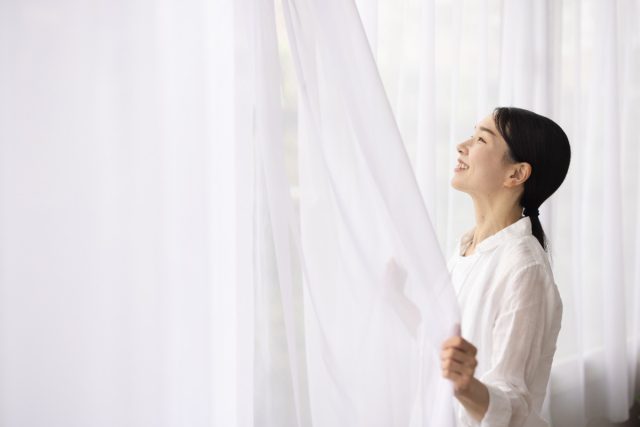 カーテンを開ける女性