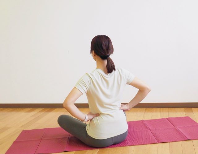 腰に手を当ててあぐらで座る女性