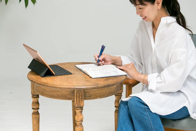 机でノートを書く女性