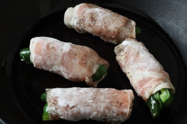 フライパンに並べたピーマンの肉巻き