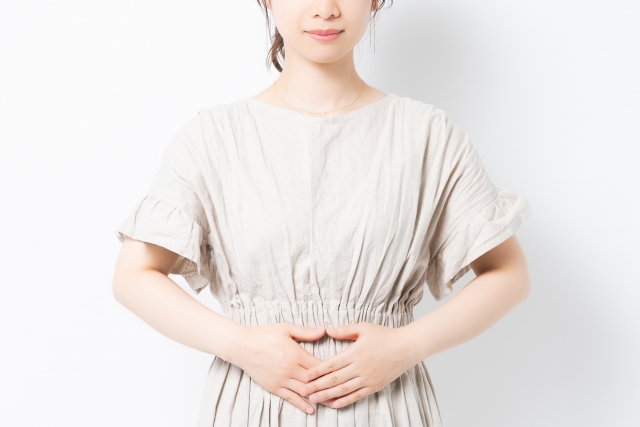 お腹に手を当てる若い女性