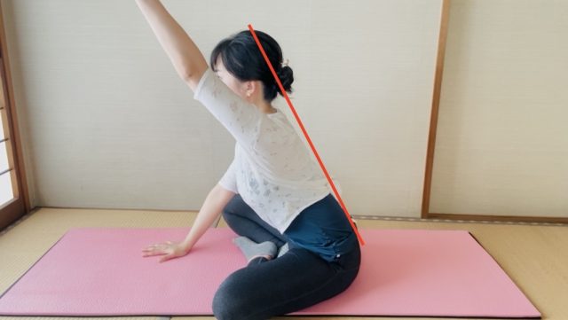 あぐらで座り背筋を伸ばして左手をあげた姿勢