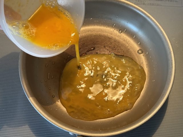 フライパンに卵を流し入れる