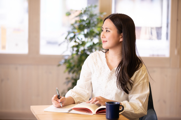 笑顔でノートを書く女性