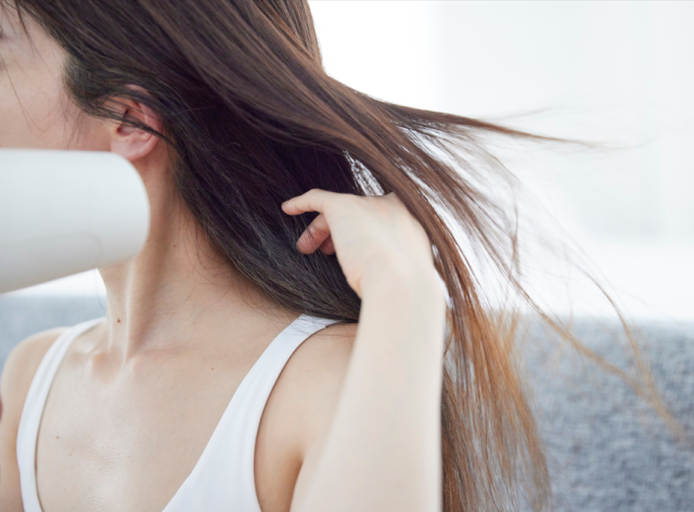 ドライヤーで髪を乾かす女性
