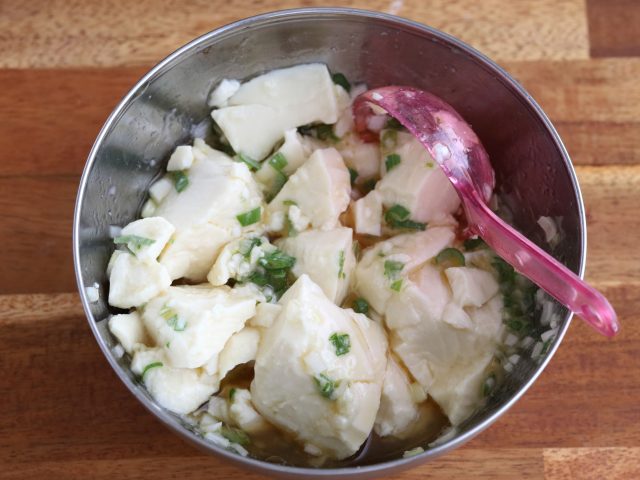絹ごし豆腐とねぎ塩だれを和える様子