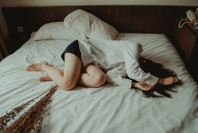 ベッドの上で落ち込む女性
