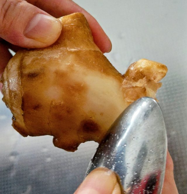 スプーンで生姜の皮をこそげ取っている様子